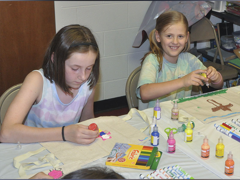 Bailey Abbot, left, and Kristi Holland decorate their Bible cases during arts and crafts at Pleasant Hill Baptist Church’s VBS Wednesday, June 9.