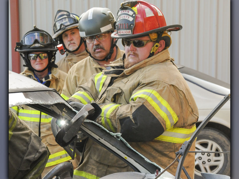 Carl Raymond, third from left, instructs Fannin County firefighters, from left, Virginia Jones, Randy Seers and Matthew “Big Money” Karry, in the latest extrication techniques to remove patients from wrecked vehicles. This was part of a refresher course taught by Raymond Wednesday, June 23, in Blue Ridge.