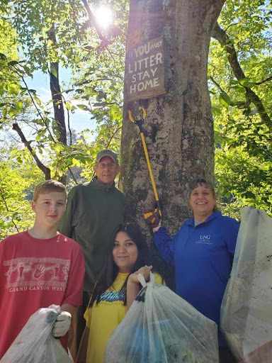 Blue Ridge Mountain Trout Unlimited Member Sandy Reinauer snapped this picture during Rivers Alive Saturday, September 25, while his group was cleaning the upper Toccoa River. A sign hidden from view urges, “If you must litter, stay home.” Shown with part of the trash they collected are,  from left, front row, University of North Georgia students David Britain and Macy Ruiz; and back row, Blue Ridge Mountain Trout Unlimited Member Bob Murrah and University of North Georgia Professor Anna Speessen.