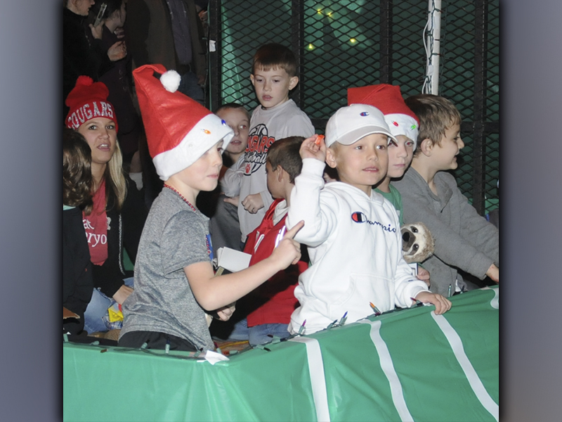 A young man throws candy to the crowd gathered for the Ducktown Christmas parade while  his friend  urges him to be careful.