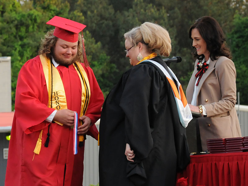 Brock Whitaker receives his Honor Cord from Amber Daly as Copper Basin High School Principal Holly Smith looks on.