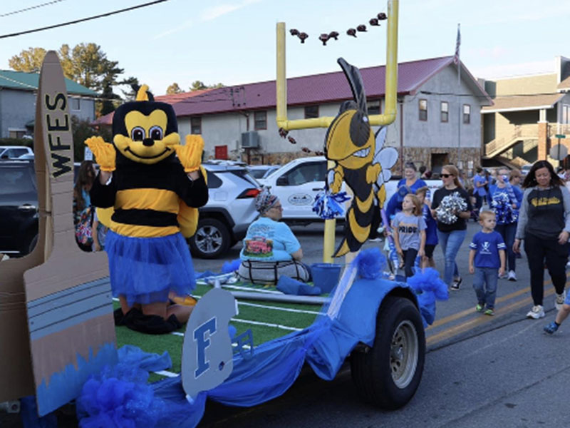 West Fannin Elementary School’s Yellow Jacket waves from the float while Principal Alison Danner walks behind with a group of students in the Paint the Town Blue Homecoming Parade through downtown Blue Ridge Tuesday, October 11. 