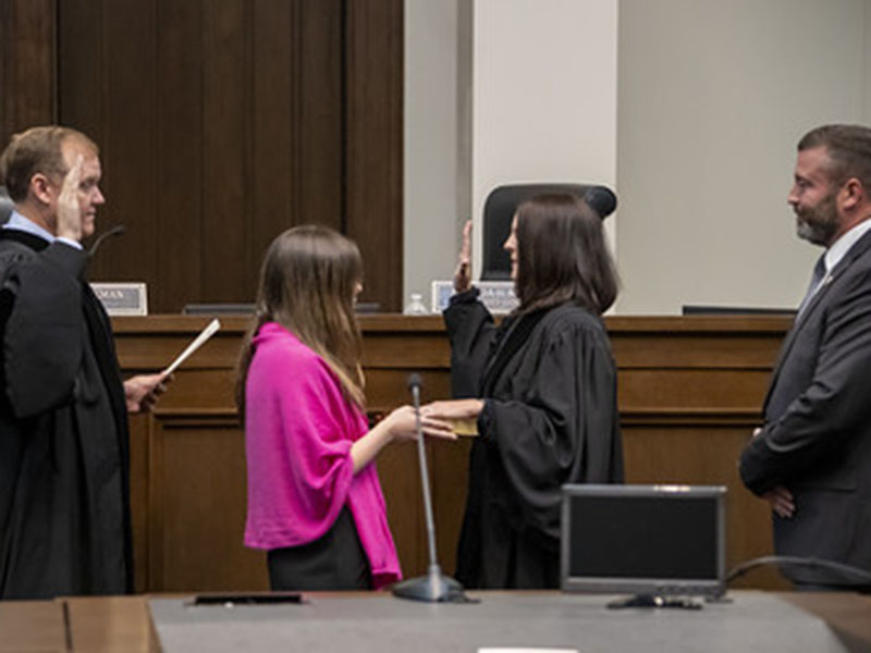 Amanda Mercier takes her oath as the Chief Judge of the Georgia Court of Appeals from Judge Brian M. Rickman  who she is succeeding. Holding the Bible is daughter, Alexandria, as husband, Joe Foster, watches the event.