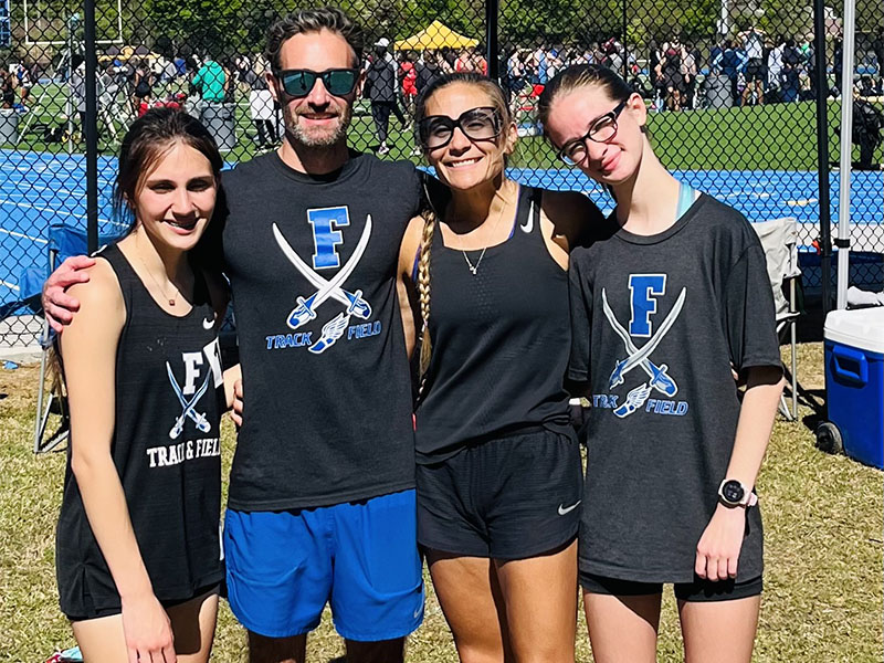 Karli Sams, Coach Dr. Lucas Roof, Coach Miranda Roof, and Sydney Ford, from left, take a break at the McEachern Invitational. Sams placed fifth in the 3200 meter run.