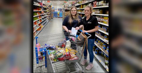 Hannah Ritchie, left, and Ashton Davis are shown gathering groceries for an elderly woman Thursday, March 26. The elderly woman could not go out and get essentials and had no one to make the trip for her.
