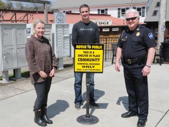 Blue Ridge City Council members Rhonda Haight and Nathan Fitts, and Police Chief Johnny Scearce, from left, are shown with one of the signs placed downtown to remind everyone to shelter in place.