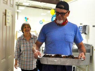 A volunteer appreciation lunch was hosted by Fannin County Family Connection to show appreciation for their volunteers, on the anniversary of the move-in day at their current facility. Jim Yacavone carries in a pan of grilled chicken while Executive Director Sherry Morris smiles wide.