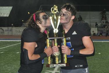 Andrew Waldrep (1), left, and Seth Reece (5) kiss the tropy they have worked for all season long. The Rebels claimed the region title Friday, November 5, after their 21-17 win over Dade County.