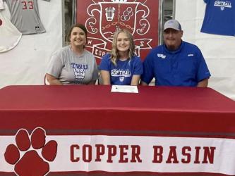 Copper Basin senior softball player Channing Beach smiles after signing her letter of intent to play softball at Tennessee Wesleyan University Thursday, May 5. She is accompanied by her parents Tina Hayes and BJ Howard.