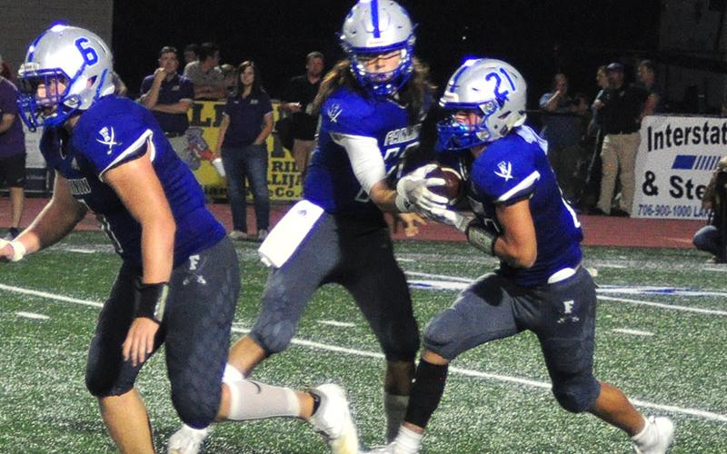 Jakob Tuggle (6) throws a block while quarterback Luke Holloway (12) hands the ball off to runningback Treylyn Owensby (21) during the Rebels football game against Union County Friday, September 13.
