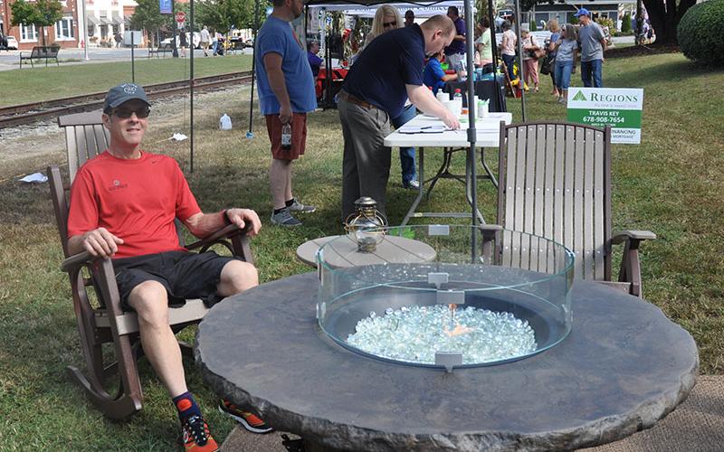 Greg Harper relaxes in a rocking chair set near a gas bonfire pit, likely imagining the set up at his house, during the Builders Showcase in downtown Blue Ridge October 5.