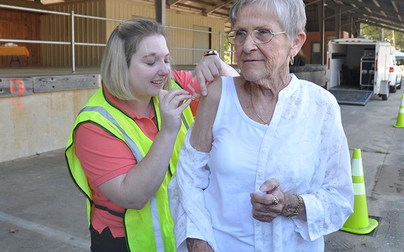 Carole Patterson stands stoic for her flu shot given by Immunization Coordinator Ashley Deverell. A drive-by flu shot clinic and mass medication drill was held at the old State Farmers Market in Blue Ridge October 3.