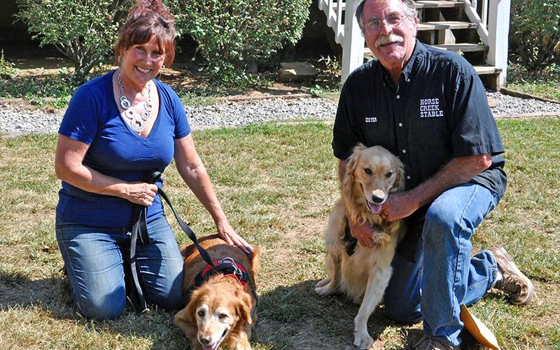 Diane Aradi smiles while petting the newest addition of their family Goldie. Also shown is husband Lester with rescue Hope. Hope was born with Cerebellar Hypoplasia. The condition affects the dog’s fine motor skills, balance and coordination.