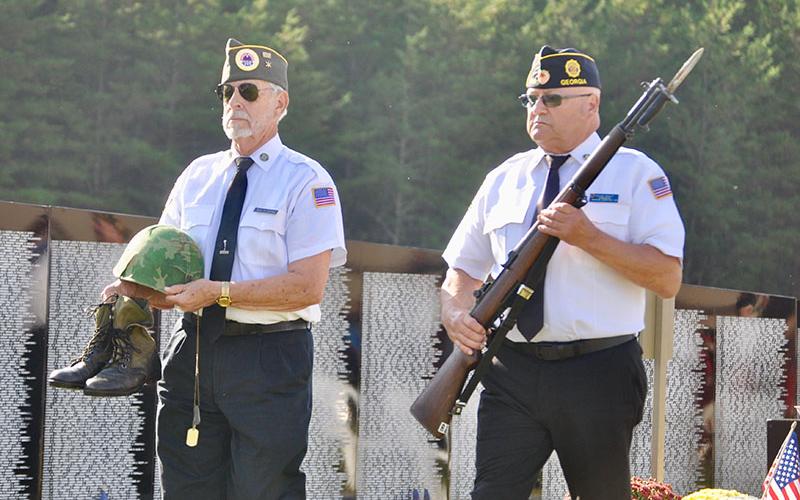 North Georgia Honor Guard members Steve Strickland, left, and Richard Crosley carry the boots, helmet, dog tags and rifle for the tribute to the fallen soldier during the The Vietnam Traveling Memorial Wall memorial service.