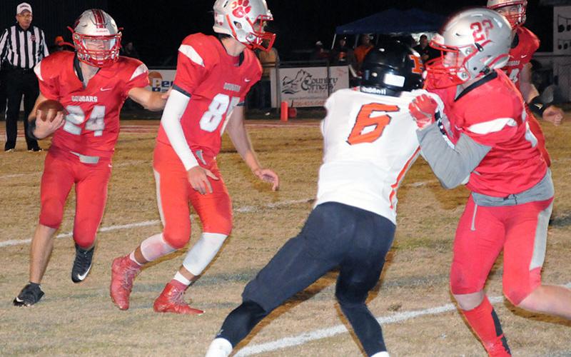 Cougar Chase Mickens (24) runs the ball while Cody Montgomery (85) looks for a defender to block and Eli Patterson (22) holds off a defender.
