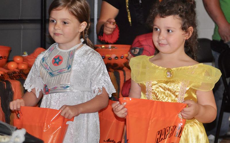 Ellie Griggs, left, and her classmate Bristol Cash collect candy as they trick-or-treat at West Fannin Elementary School.