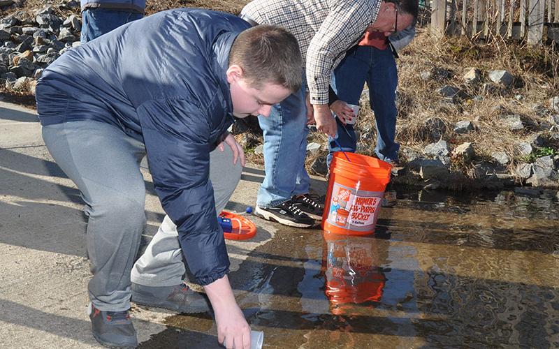 The Blue Ridge chapter of Trout Unlimited facilitated a trout life-cycle program, Trout in a Classroom, at Fannin County Middle School where the eighth-graders raised trout from eggs and then released them into the Toccoa river, December 18. Shown is Ridge Stevens pouring a trout fingerling into the chilly water.
