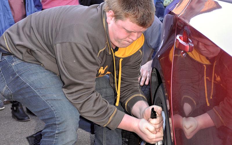 Fannin County High School Student Logan Stiles strains to take the lug nuts off a car Thursday, December 5.