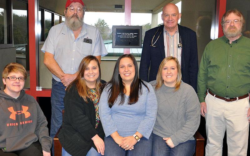 Family and friends gathered Monday, December 16, at the Riverstone Medical Campus in Blue Ridge to honor those who died in a plane crash near Blairsville Municipal Airport December 19, 2018. Gathering on and around a bench dedicated to the deceased are, from left, front row, Survivor Brittany Whitener, Michelle Seay’s daughters Anna Deyton, Katie Bergen and Brittany Combs; back Renea Greiner’s husband Richard, Dr. Raymond Tidman and Dr. Stan Trigg.