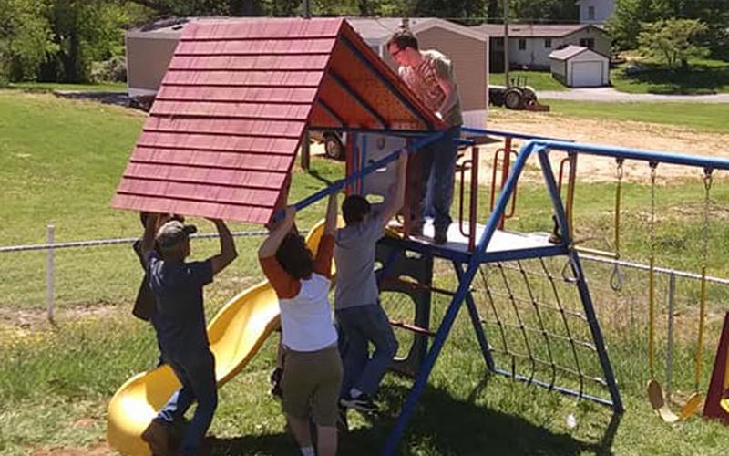 Andrew Monroe and fellow Boy Scouts place a roof on the playset for Fannin County Preschool’s playground.