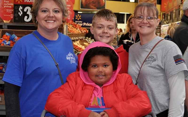 Memori Sorensen, front, pushes the buggy while searching for some presents with Shop with a Cop Board Member Dawn Cochran, left, Volunteer Steven Dickey and Board Member Sarah Dickey.