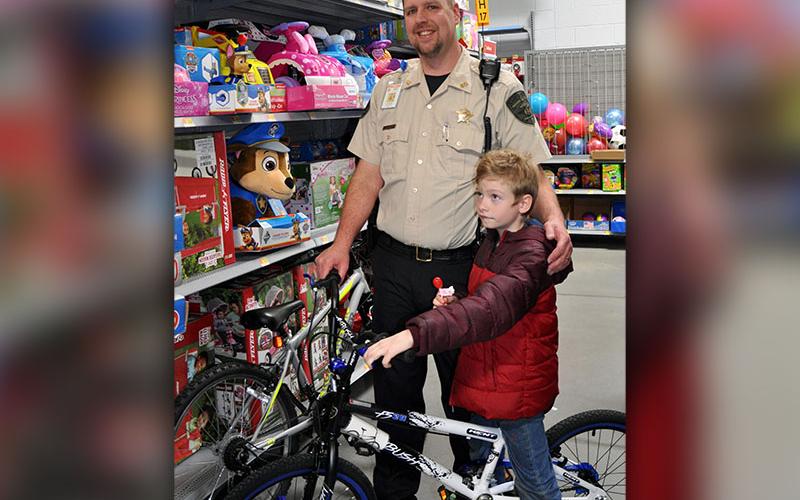 Fannin County Deputy Sheriff and School Resource Officer Jim Burrell smiles while Damian Long tests out a bicycle during Shop With A Cop. .