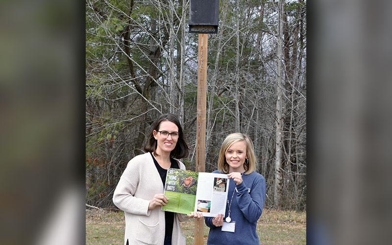 Parent Jocelyn Miller, left, and West Fannin Elementary teacher Katy Roberson show off their article in the January 2020 issue of “Science and Children.” Behind the two is a bat box that was designed and constructed by Roberson’s first grade students.