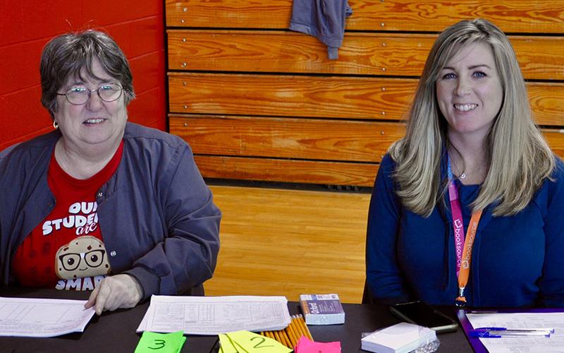 Teachers and volunteers Barbara Dobbins, left, and LeAnn Dockery wait for more families to come in so they can keep count of how many have been served. They said their food bank usually serves 250 families in the area.