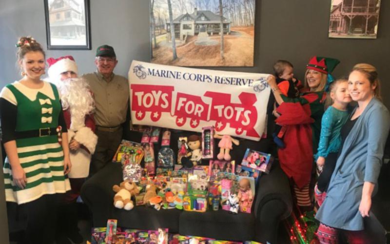 Magalie Dean, from left, Santa, Jim Brumbelow, Ryan Sisson, Tracie Griffith, Claire Sisson and Amber Sisson smile while representing Tru Mountain Reality for this year’s First Community Mortgage Toys for Tots Challenge.