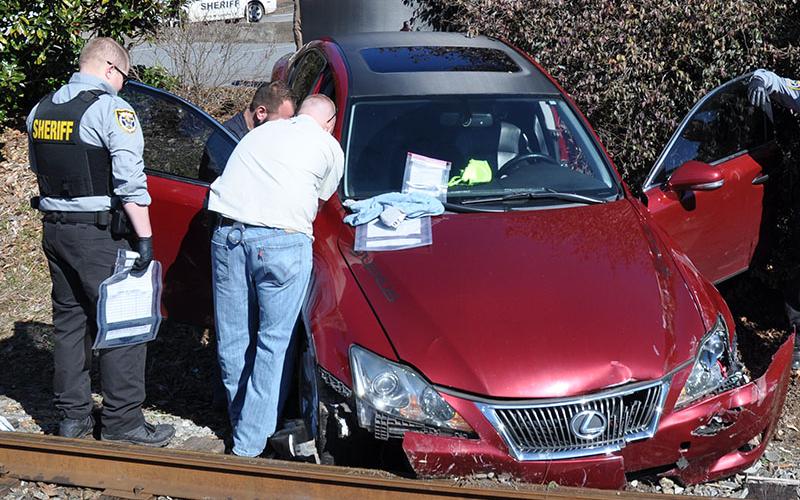 The Lexus Matthew Alexander Rich was driving came to rest wedged between the railroad tracks and an embankment between Hometown IGA and St. Catherin Laboure Catholic Church. Searching the car are Polk County Deputy Sheriff Manuel Patterson, Detectives Josh Stroud (partially hidden) and Jake Wallace. After the crash, Rich fled on foot along the railroad tracks before finally being caught across from the McCaysville First Baptist Church by Wallace, Stroud and Patterson.