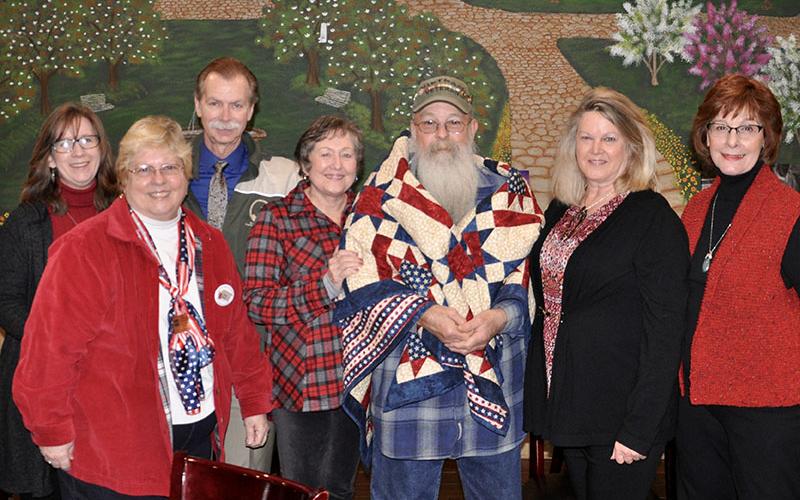 U.S. Army Vietnam veteran Chuck Bowen III, adorned with a quilt, was honored for his military service Wednesday, January 29. Around him are, from left, Rhonda Worthingstun, Quilts of Valor Foundation Laison Susan Young, Dean Worthingstun, Bowen's wife Susie, Bowen, nominator Lauren Lancaster and quilter Robin Czyscon.