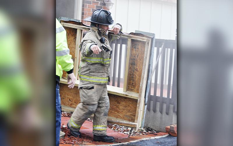 Fannin County firefighter Jason Turner removes part of a covering in order to access the crawl space under the house at 511 Scenic Drive.