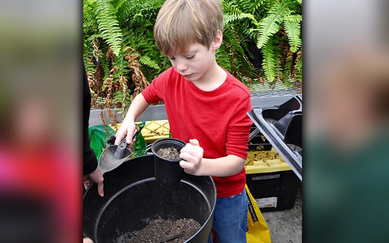 Yates Eagenson fills his pot up with dirt before planting a seed during the special class.