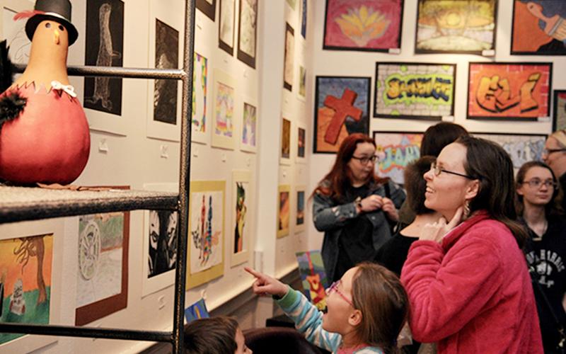 Charity Roderick, an 8-year-old homeschool student and award winner in the homeschool division, admires the artwork on display at Blue Ridge Mountains Arts Association’s Youth Art Month opening reception Thursday, February 27. She is accompanied by mother Jennifer and brother Charlie.