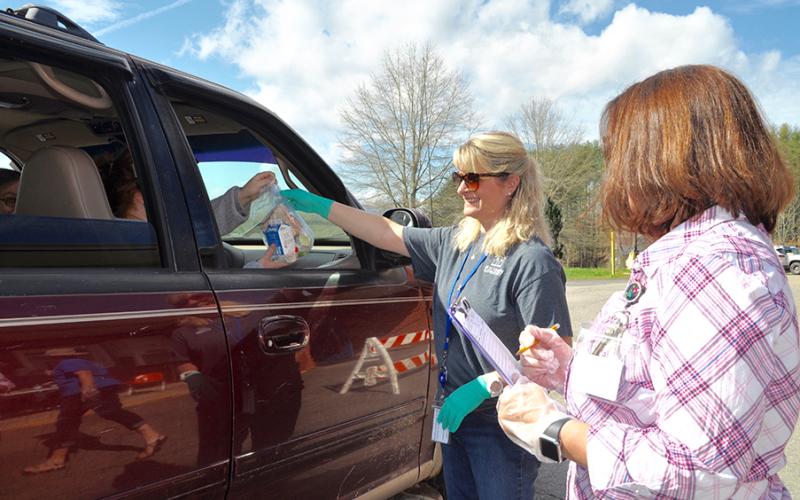 East Fannin Elementary School teacher Kathy Culpepper hands a pre-packaged meal to a Fannin County family, while teacher Christie Holtman documents it, during the school closure caused by COVID-19.