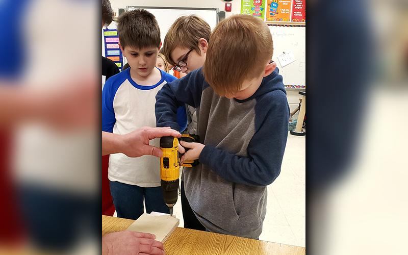 Mitchell Martin, Christian Highley and Brody Golden, from left, worked to get parts ready for a soap box derby car at East Fannin Elementary School.