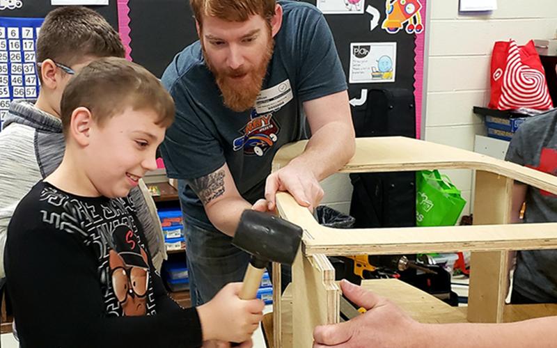 Mike Sullivan, right, helped Aryan Pack, left, and Hayden Bryan put together a soap box derby car at East Fannin Elementary School last week.
