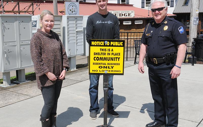 Blue Ridge City Council members Rhonda Haight and Nathan Fitts, and Police Chief Johnny Scearce, from left, are shown with one of the signs placed downtown to remind everyone to shelter in place.