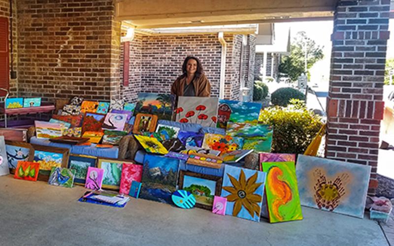 Jennifer Danner stands behind a plethora of paintings created by herself and other members of the community for the residents at the Life Care Center of Copper Basin. The paintings were delivered Thursday, April 2.