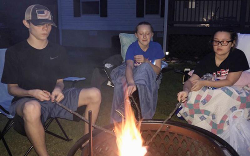 Fannin County Middle School student Jordan Buchanan, left, and Fannin County High School students Jasmine Jackson, middle, and Madison Buchanan enjoy making s’mores and staying warm by a fire pit while they are out of school.