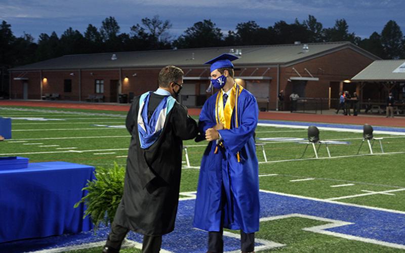 Fannin County graduate Gabe Buchanan bumps elbows with Principal Erik Cioffi after receiving his diploma during the Fannin County High School 2020 graduation.