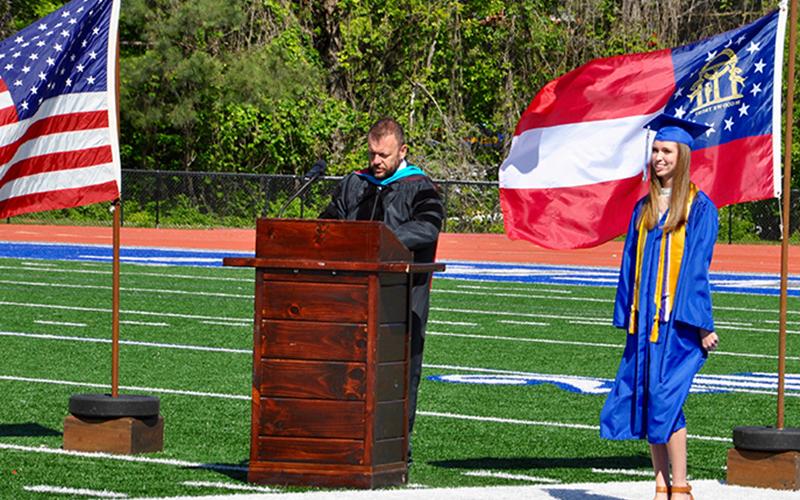 Abigail O’Neal stands ready before walking the Fannin County High School football field to receive her diploma during a private graduation ceremony. Assistant Principal Scott Ramsey stands at the podium to announce each graduate.