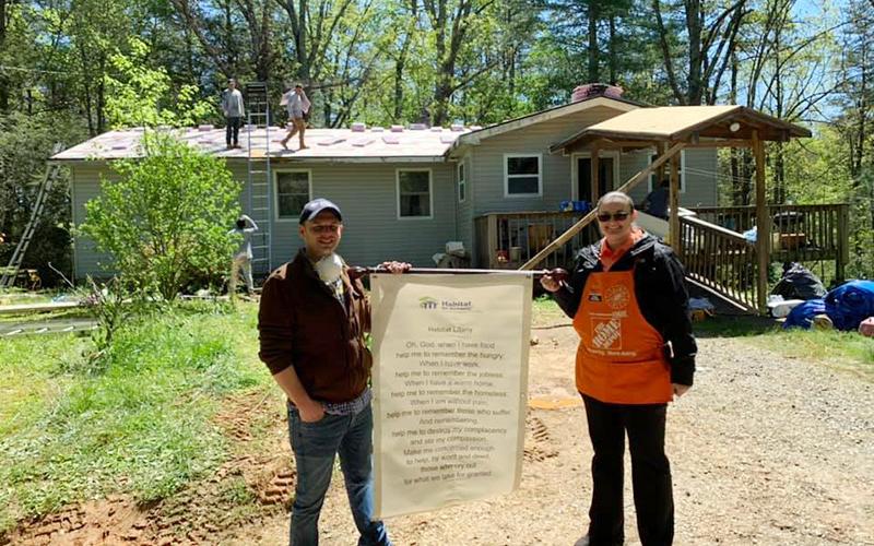 Habitat for Humanity of Fannin and Gilmer Counties Executive Director Chris Hall holds their mission statement, alongside Holly Chandler of Home Depot, during a recent roofing project.