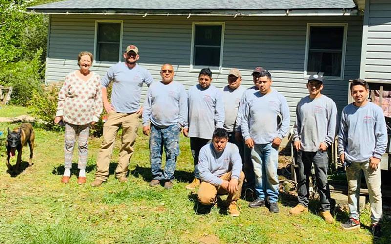 Virginia Card stands beside Semper Fi Roofing and Restoration Owner Nick Black and workers while having her roof repaired.
