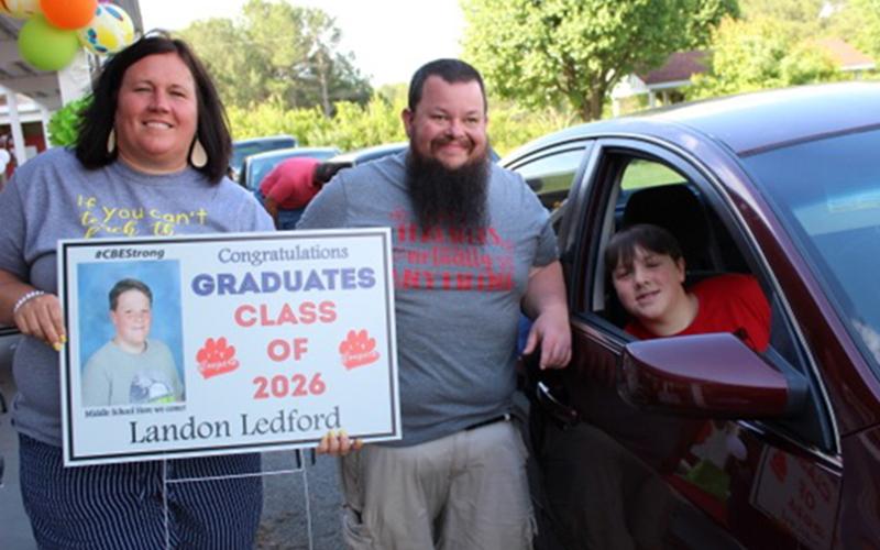 CBES teachers Jennifer Speights and Andrew Cook give sixth grade graduate Landon Ledford his things during the drive-thru graduation Tuesday, May 26.