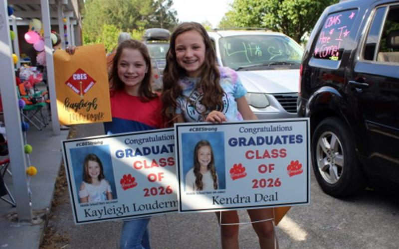Copper Basin Elementary School graduates Kayleigh Loudermilk and Kendra Deal show off their signs at the CBES drive-thru graduation Tuesday, May 26.