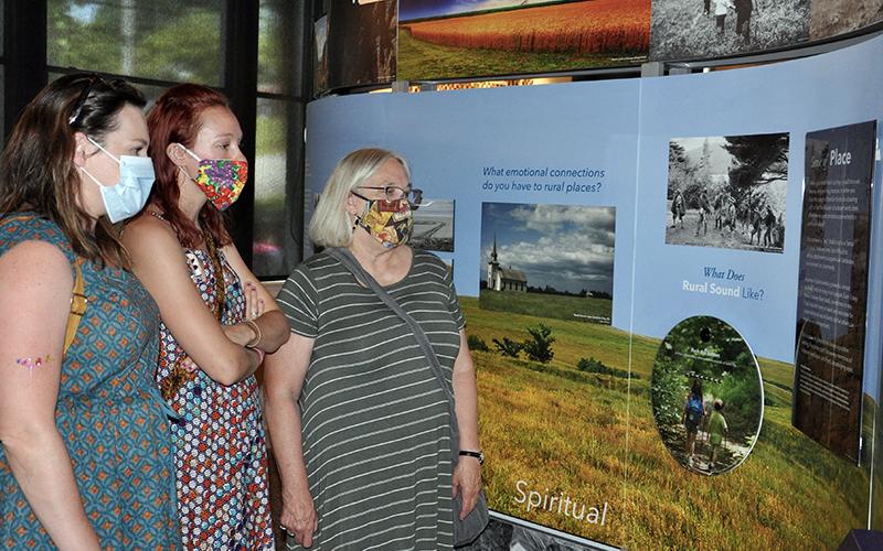 Crossroads: Change in Rural America Co-Curator Dr. Ann McCleary, right, explains the exhibit to, left, Sarah Wright and Emma Bussard at the exhibition’s grand opening Saturday, June 20.