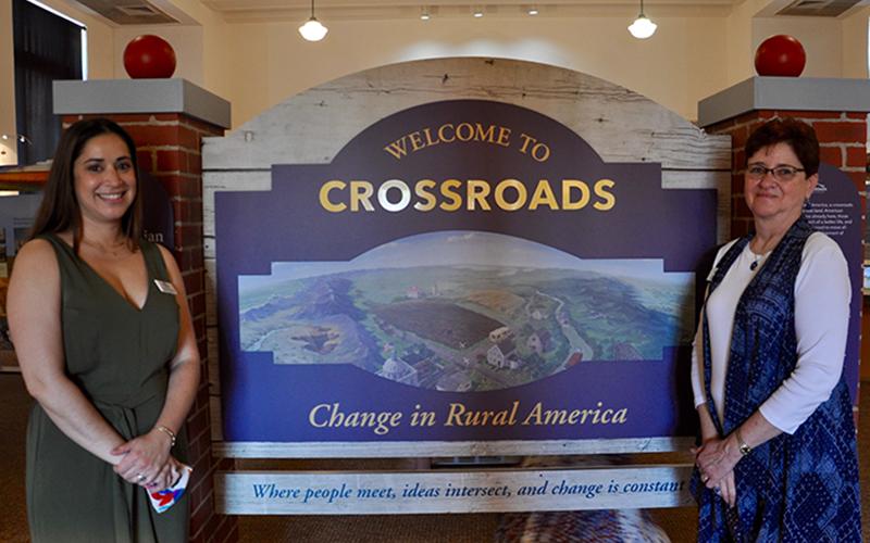 Blue Ridge Mountains Arts Association Executive Director Nichole Potzauf, left, and Assistant Director Caroline Mann stand before the long-awaited “Crossroads: Change in Rural America” exhibition Saturday, June 20. The exhibition is in partnership with the Smithsonian Institute’s Museum on Main Street, Georgia Humanities, the University of West Georgia and Georgia EMC. It will continue at The Art Center through July 17.