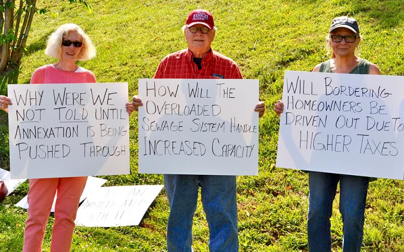 Libby Young, Kirk Williams and Dana Worm waited outside Blue Ridge City Hall holding signs with questions regarding the proposed annexations of highways 5 and 515.