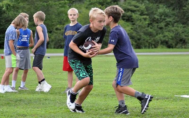 Toccoa Pugh takes a hand off during the Rebels football practice at the rec center Tuesday, July 21.